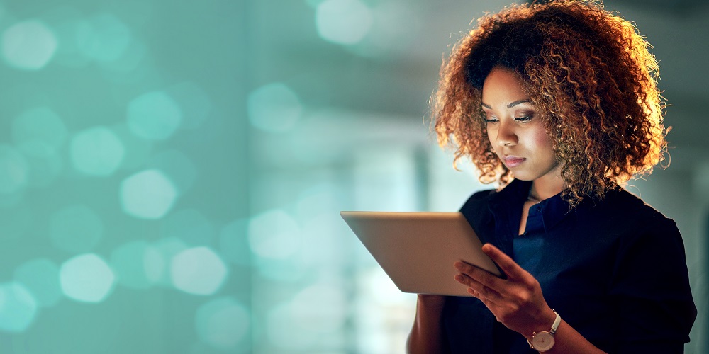 A woman is focussing on her tablet.